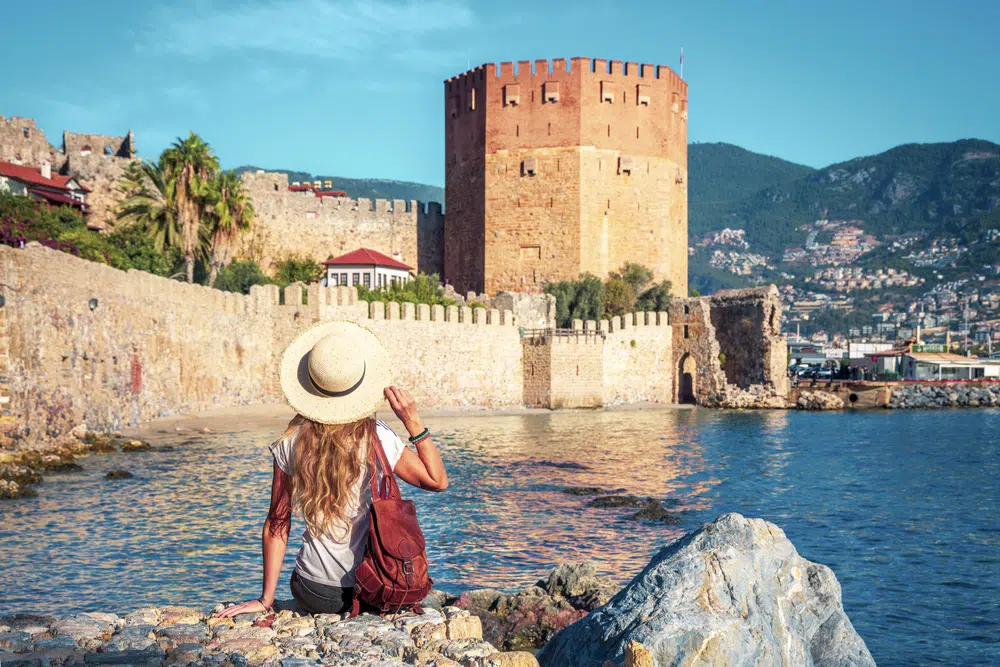 young female tourist looking at red tower in alanya, antalya in turkey