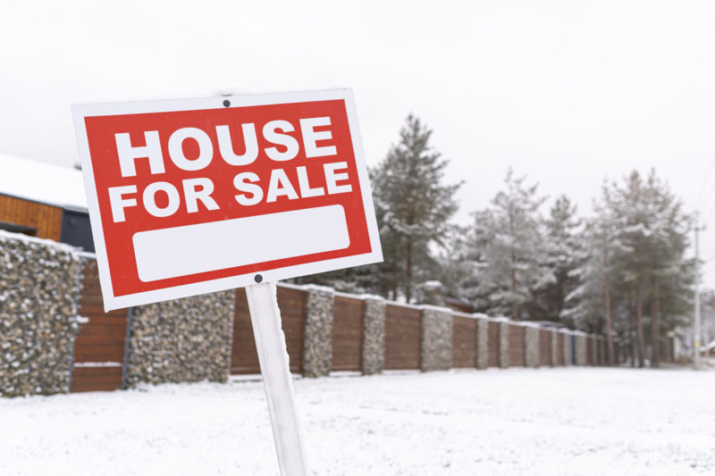 red sign house for sale, outdoors in winter. buying suburban real estate