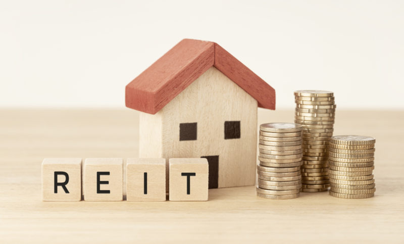 reit real estate investment trust concept. house model, money and wooden blocks with text