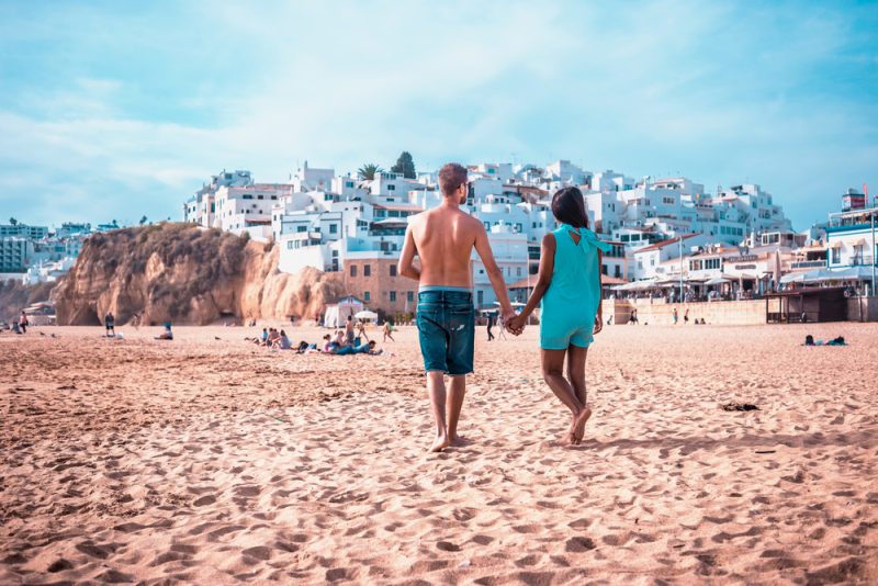 happy young couple walking at the beach of albufeira algarve portugal